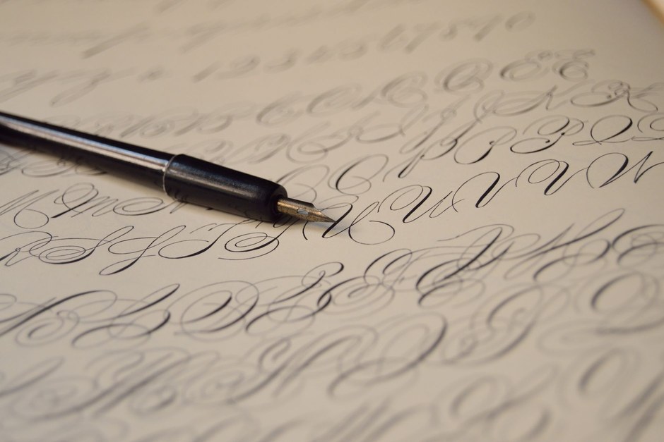 Fountain pen writing cursive practice letters across a sheet of paper
